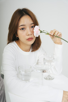 亚洲女人的时尚肖像，桌上拿着一朵花和一包水杯。