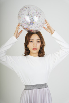 美丽的亚洲年轻女子，白色背景上有闪闪发光的塑料球。