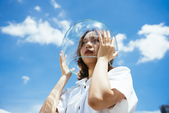 一位戴着玻璃碗的亚裔妇女像宇航员一样保护自己免受地球上的污染。