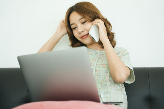 亚洲女人在家里用智能手机和笔记本电脑聊天。