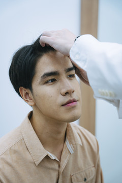 美容师在美容诊所检查年轻人的面部进行面部治疗。