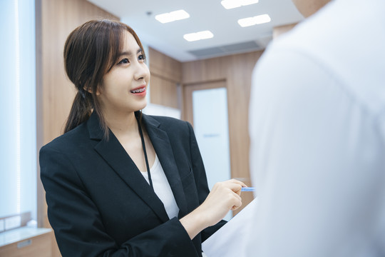 年轻漂亮的亚洲女商人穿黑色夹克给办公室的合伙人提建议。