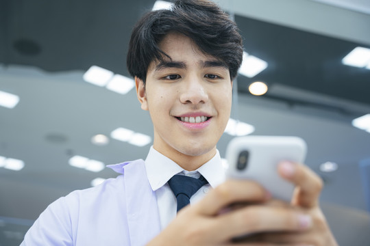 年轻的亚洲医生在医院用智能手机和病人发短信的照片。