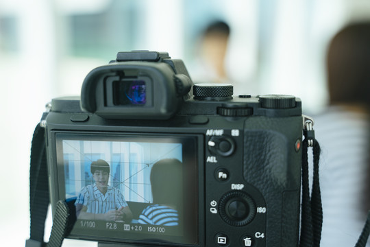 内容创作者和影响者接受记者采访，前景三脚架上的摄像机屏幕。