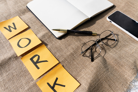 棕色桌子上摆着一张写字台，上面有钢笔、眼镜和智能手机。