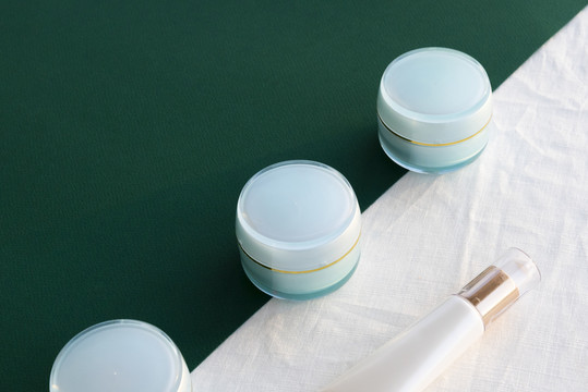 绿色和白色背景上的海蓝宝石化妆品奶油罐。