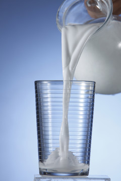 一壶牛奶倒进玻璃杯里。