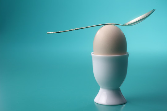 用勺子把天平放在鸡蛋上面