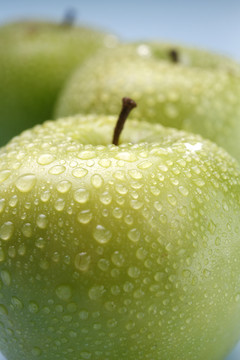 在彩色背景上被水滴覆盖的湿绿色苹果。隔离。