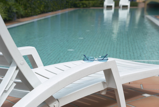 太阳镜放在靠近游泳池的空座位上休息。