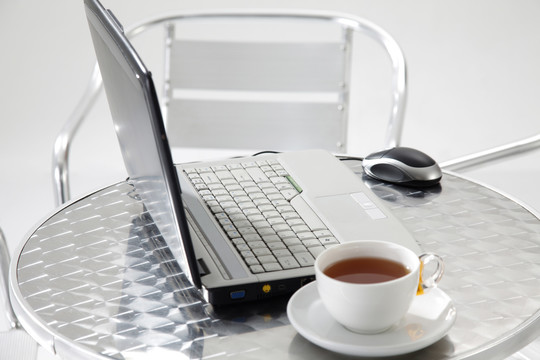 桌上放着一台笔记本电脑和一杯茶