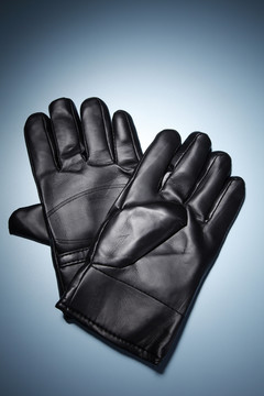 蓝色背景上隔离的一副黑色手套。