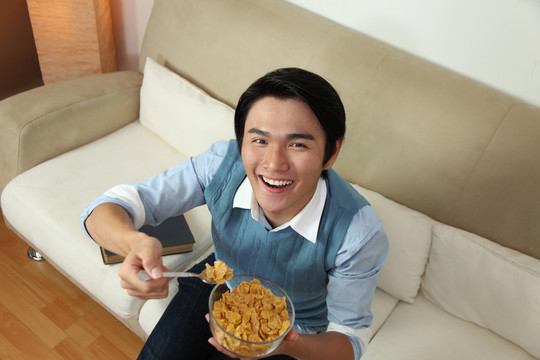 微笑的男人在吃一碗麦片