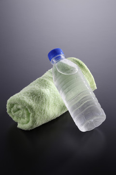 瓶装水和灰色背景上的毛巾