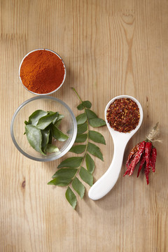 木制背景上的辣椒、辣椒粉和咖喱叶