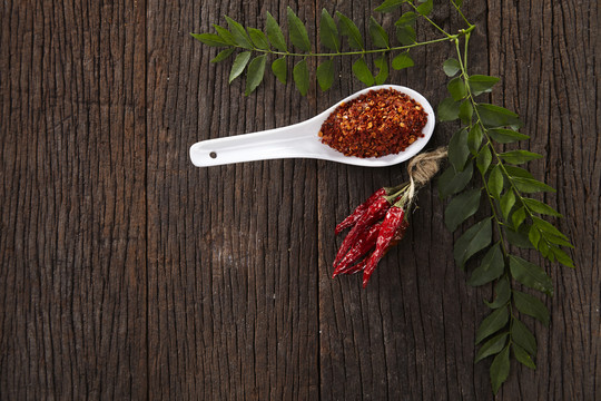 木制背景上的辣椒、咖喱叶和粗辣椒粉