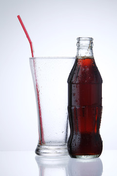 一瓶可乐汽水和一杯冰隔离在白色背景上