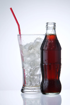 一瓶可乐汽水和一杯冰隔离在白色背景上