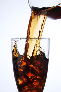 把可乐饮料倒进加冰的玻璃杯里
