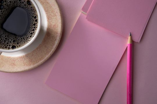 咖啡饮料顶视图和粉红色背景上的空白便笺簿