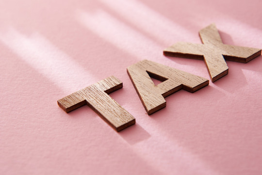 粉红色背景上的木制字母税