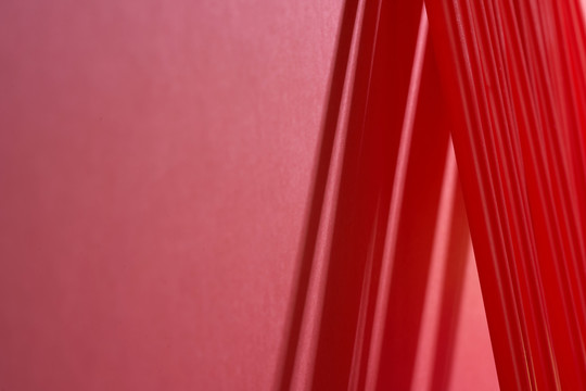 一排红色塑料吸管斜靠在红色背景的墙上