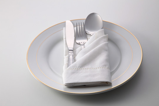折叠餐巾，带叉子、勺子和刀，盘子上