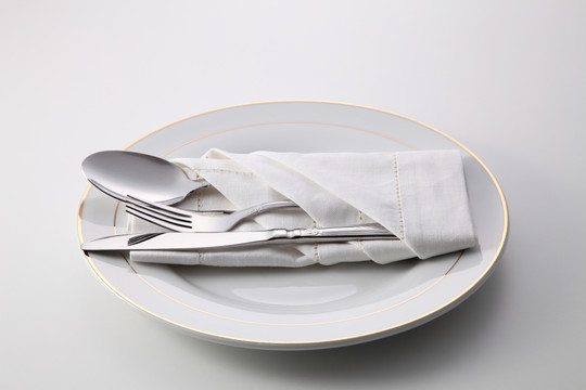 折叠餐巾，带叉子、勺子和刀，盘子上