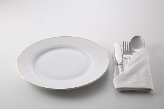 折叠餐巾，餐叉、汤匙和刀子放在盘子旁边