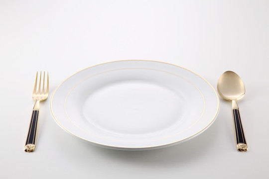 空盘子旁边放着金色的叉子和勺子