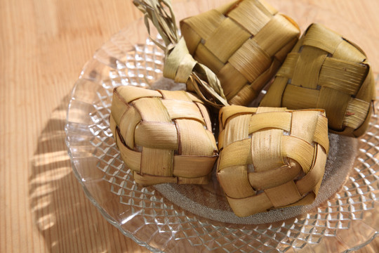 木制背景上的饺子。Ketupat是一种天然米壳，由年轻的椰子叶制成，用于在穆巴拉克开斋节期间煮饭