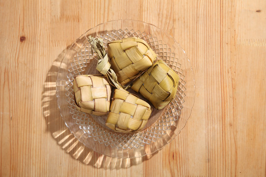 木制背景上的饺子。Ketupat是一种天然米壳，由年轻的椰子叶制成，用于在穆巴拉克开斋节期间煮饭