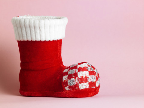粉红色背景上的红色圣诞老人的靴子