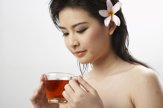 一个头发上插着一朵花拿着一杯茶的女人