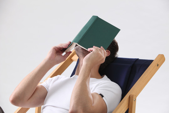 躺在躺椅上的人拿着书