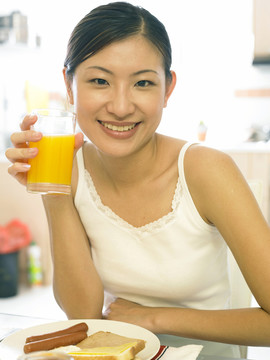 一位年轻女士在厨房里喝橙汁