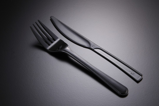 黑色背景上的一套塑料叉和刀