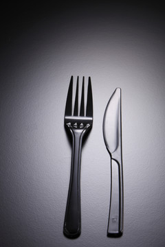 黑色背景上的一套塑料叉和刀