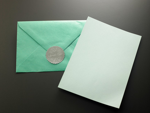 带绿色信封的空白卡片和感谢贴纸