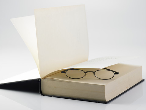 一本打开的精装书和一副阅读眼镜