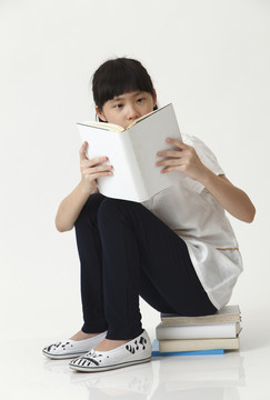坐在书堆上看书的中国女孩