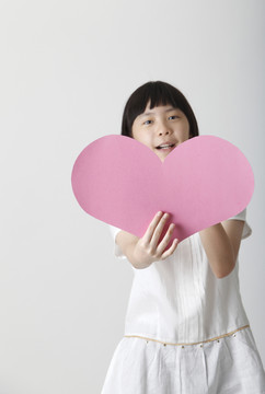中国女孩拿着一张空白的心形纸板
