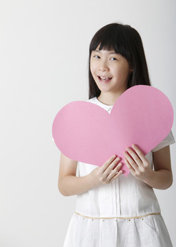 中国女孩拿着一张空白的心形纸板