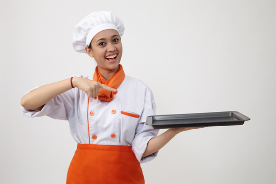 一个穿着厨师制服的印度女人拿着一个空盘子的肖像