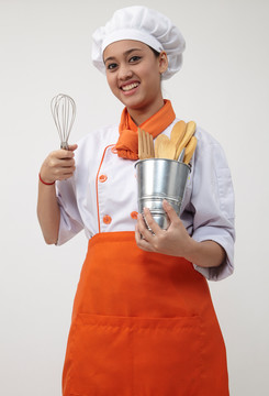 一个穿着厨师制服拿着搅拌器和抹刀的印度女人的肖像