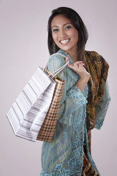 年轻的马来女子微笑着拿着购物袋