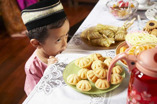 马来小男孩迫不及待地想吃桌上的食物