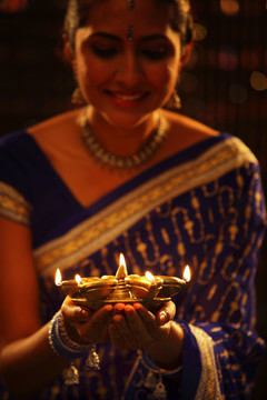 一个拿着油灯的穿着蓝色纱丽的印度女人