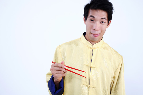 一个饥肠辘辘地拿着筷子的年轻人
