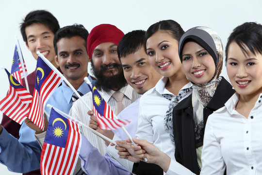 手持马来西亚国旗的多种族男女，对着镜头微笑